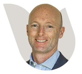 Professional headshot of a bald man in business attire smiling.